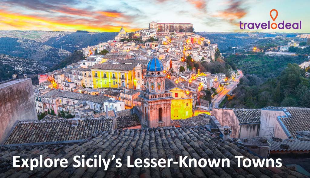 A vibrant sunset over a picturesque Sicilian town with colorful buildings, terracotta roofs, and distant hills.