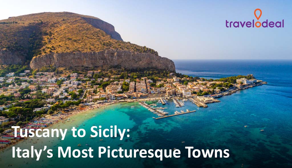 Aerial view of a picturesque coastal town in Sicily, framed by mountains and turquoise waters, under a clear blue sky.