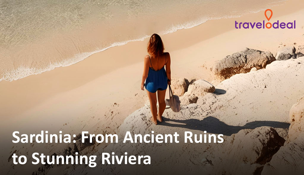 A woman in a blue dress walks along a sandy beach, gazing at the serene waves and rocky coastline of Sardinia.