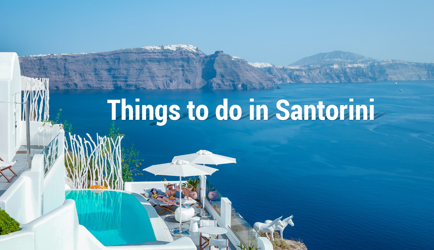 Stunning view of Santorini with white buildings, a pool, and a breathtaking blue sea in the background.